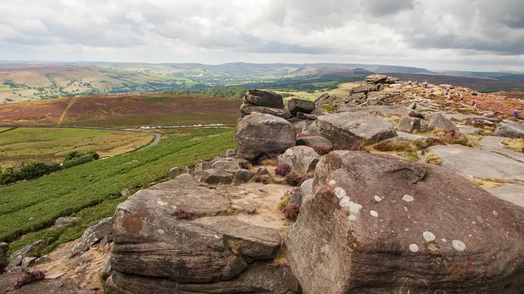 The rocks of Stanage head into the distance with the gritstone edge to the left. In the distance are the hills of the Peak District and the Hope Valley